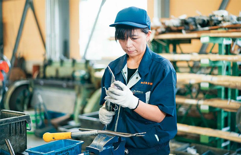 加賀発条の工場の女性社員の写真。ばねの製造は人手に頼る作業も多い。