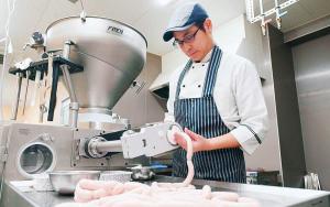 腸詰め作業の様子の写真。スタッファーと呼ばれるドイツ製の機械を使用。