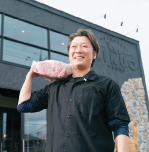 熟成中の大きなブロック肉をかつぐ中谷社長の写真