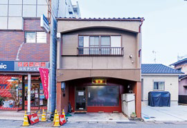 店舗の外観写真。七尾市の中心部、住宅地の中に立地する。