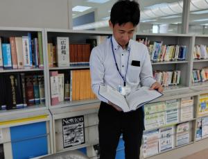 ライブラリの図書スペースで書籍を閲覧するT.Iさんの写真