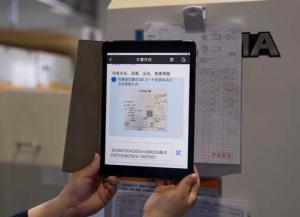 社内SNSにタブレット端末から写真や文字を投稿している様子の写真