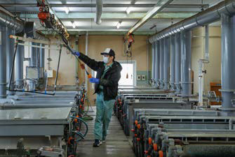 航空機部品にアルマイト処理を施す様子の写真