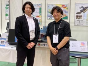 展示会で出店者の方と笑顔で写るR.Nさんの写真